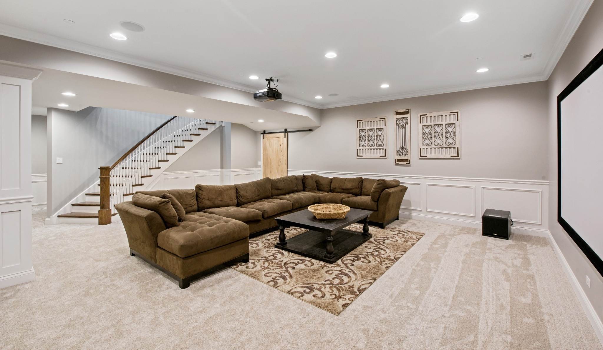 Sous-sol aménagé avec canapé sectionnel, escalier ouvert et projecteur — image d’inspiration